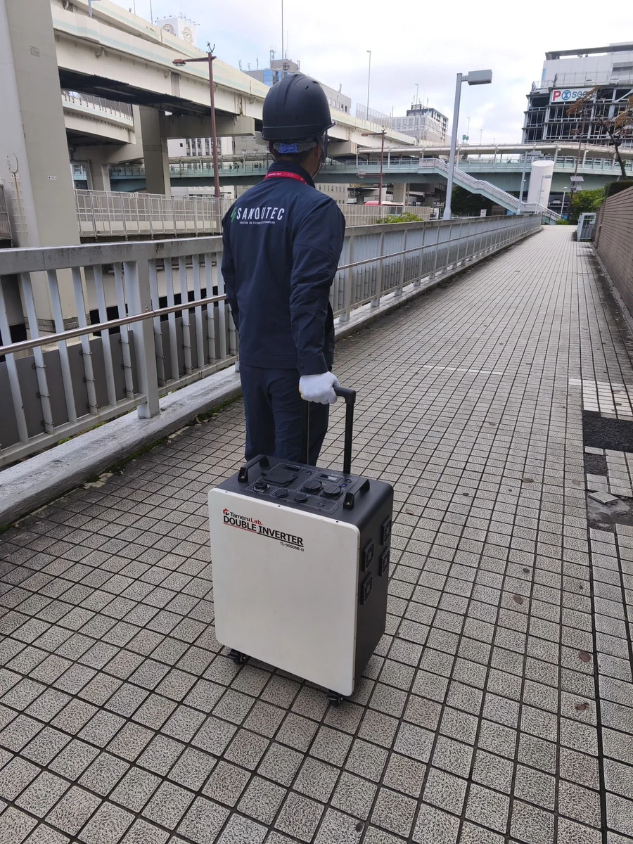 ポータブル蓄電池タメルラボ. ダブルインバーターを運ぶ作業員